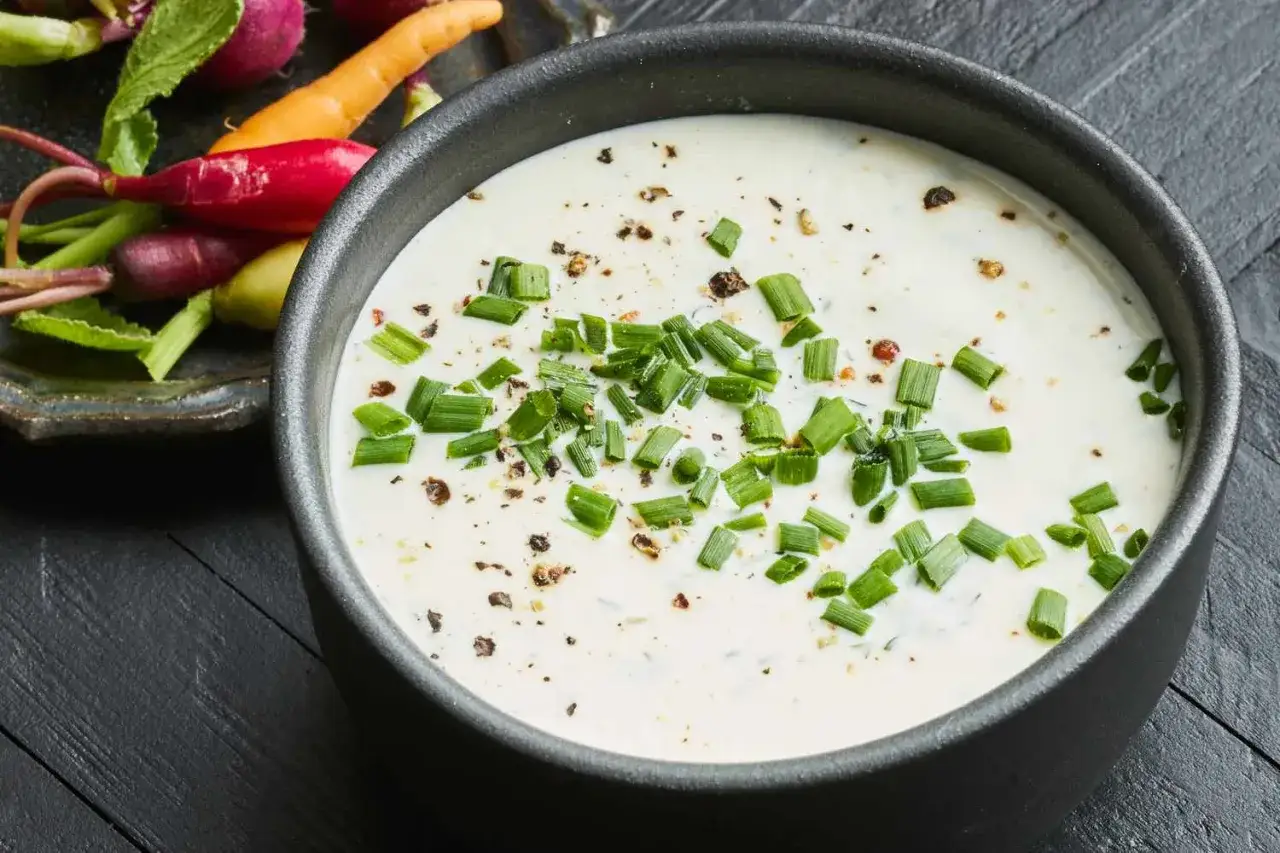 Cremiger Buttermilk Ranch Dip, garniert mit Schnittlauch und Gewürzen, daneben bunte Radieschen und Karotten. Perfekt zum Dippen!