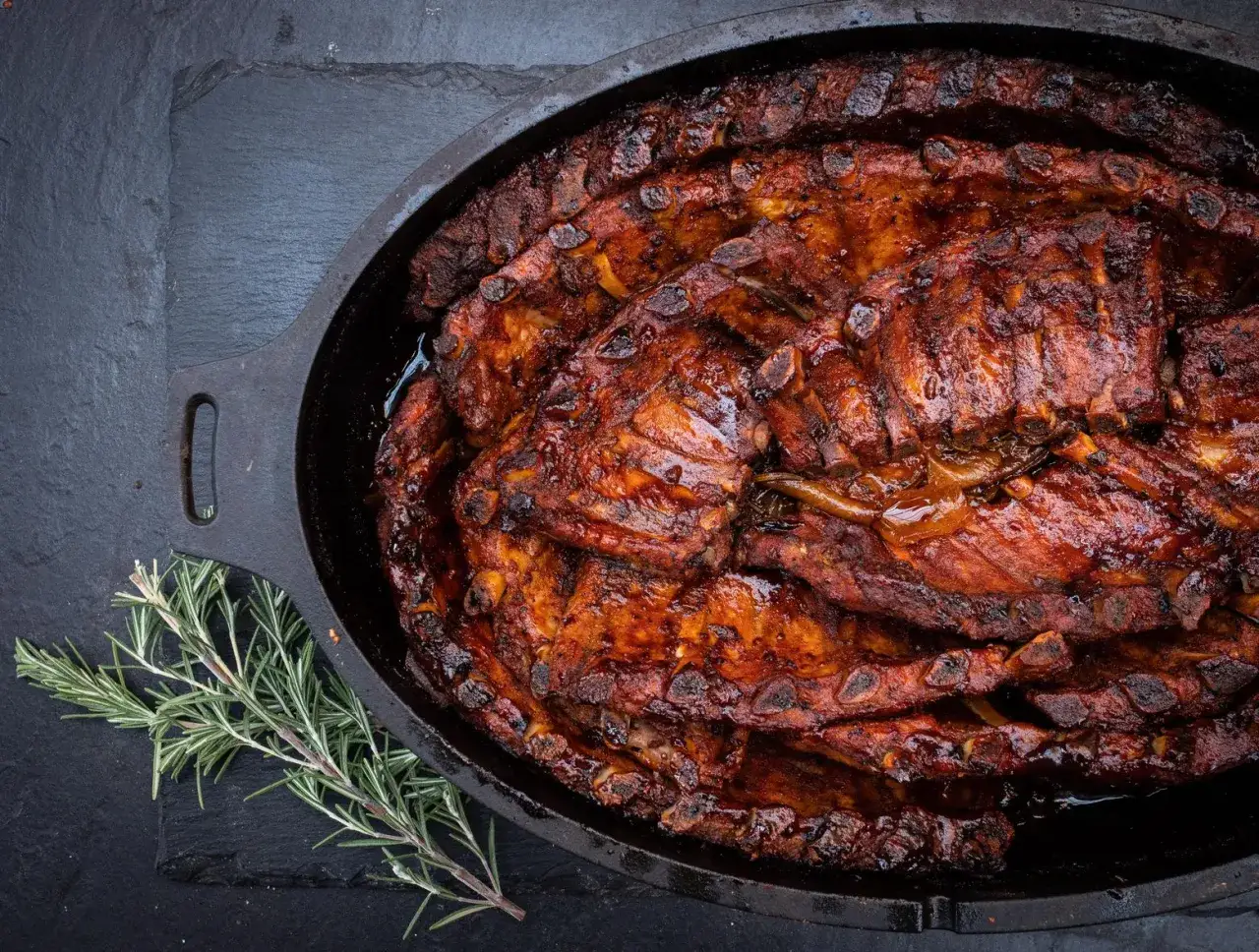 Saftige Spareribs, glasiert und geschmort im Dutch Oven, mit Rosmarin garniert.