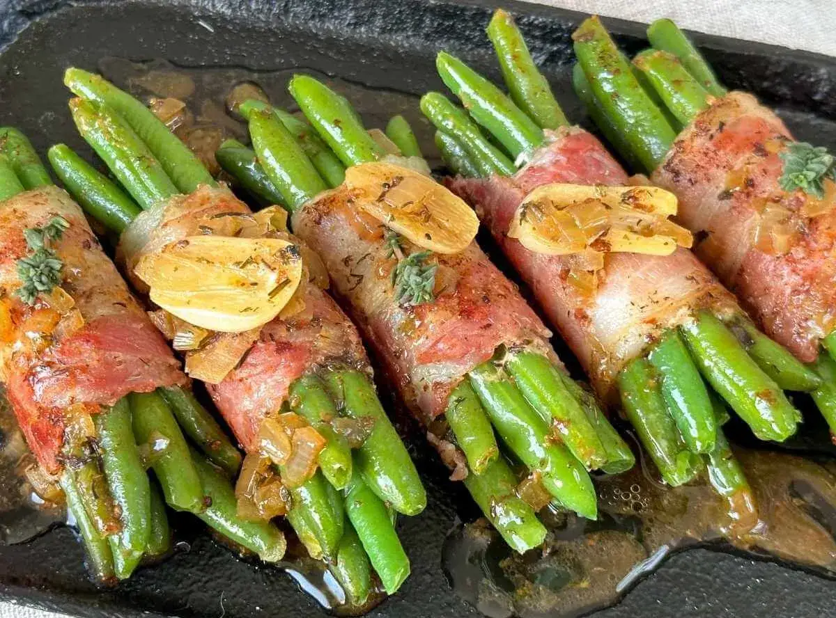 Grüne Bohnen im Speckmantel mit Knoblauch und Kräutern, frisch aus dem Backofen, glänzen in einer köstlichen Sauce.
