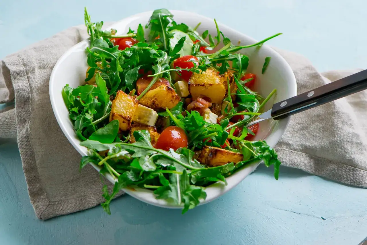 Ein frischer Salat mit Rucola, Kirschtomaten, Feta und knusprigen Kartoffelspalten.