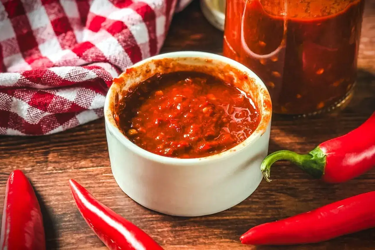 Selbstgemachte Chilipaste in einer Schale, umgeben von frischen Chilis. Perfekt f&uuml;r alle, die gerne chilipaste selber machen.