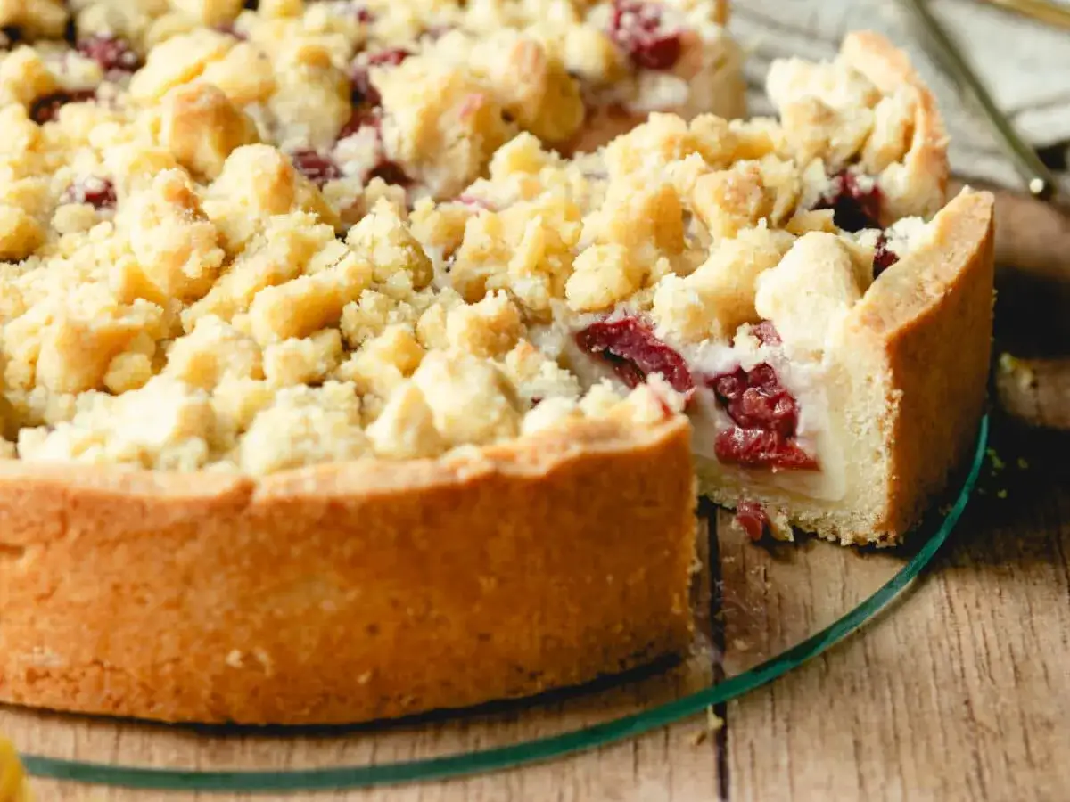 Ein saftiger Streuselkuchen mit Pudding und Kirschen, der auf einem Holztisch serviert wird.