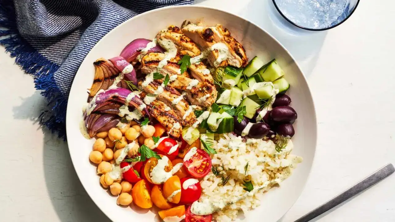 Herzhafte Bowl-Rezepte: Gegrilltes Hähnchen, Kichererbsen, Tomaten, Gurken, Zwiebeln, Oliven und Reis mit Kräuter-Dressing.