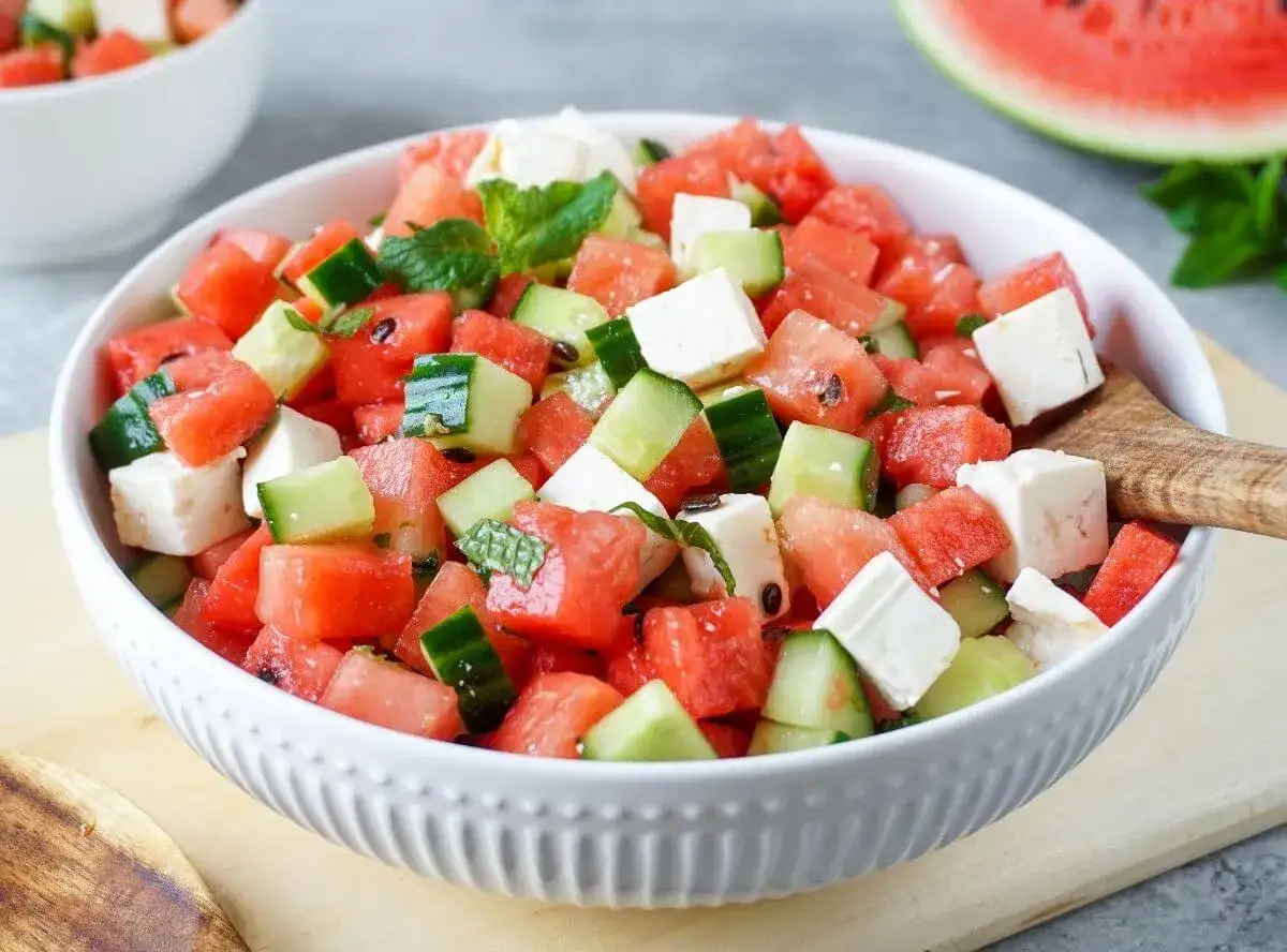 Erfrischender Wassermelonen Salat mit Gurkenwürfeln und Feta-Käse, garniert mit Minze. Perfekt für heiße Tage!