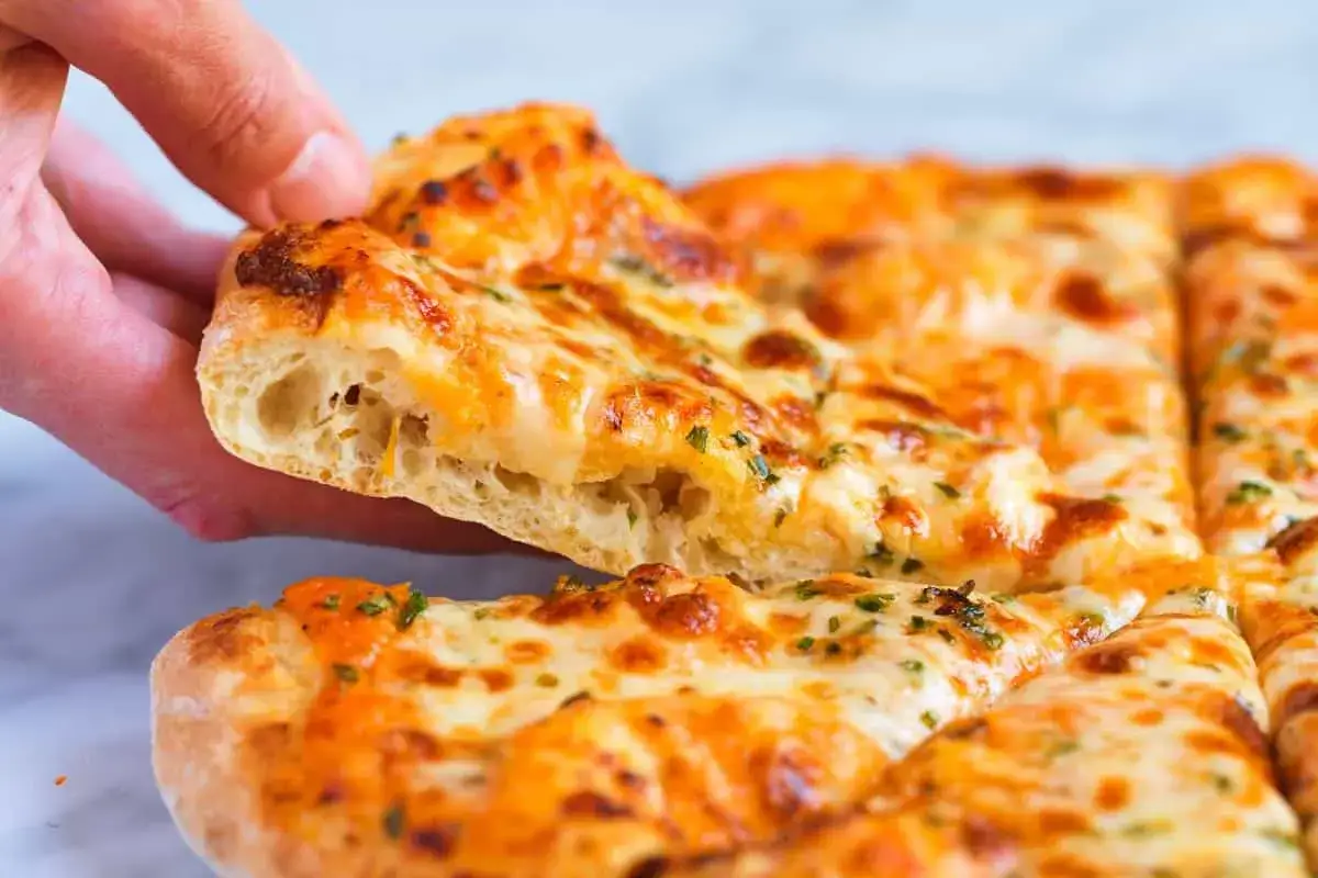 Ein Stück hausgemachte Pizza mit geschmolzenem Käse und Kräutern. Perfekt, wenn du Pizzateig selber machen möchtest!