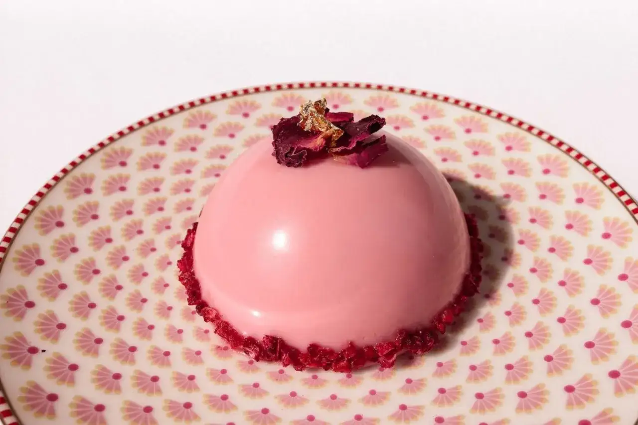 Eine zarte Mousse Torte mit gl&auml;nzender Spiegelglasur, dekoriert mit Rosenbl&auml;ttern und Blattgold.