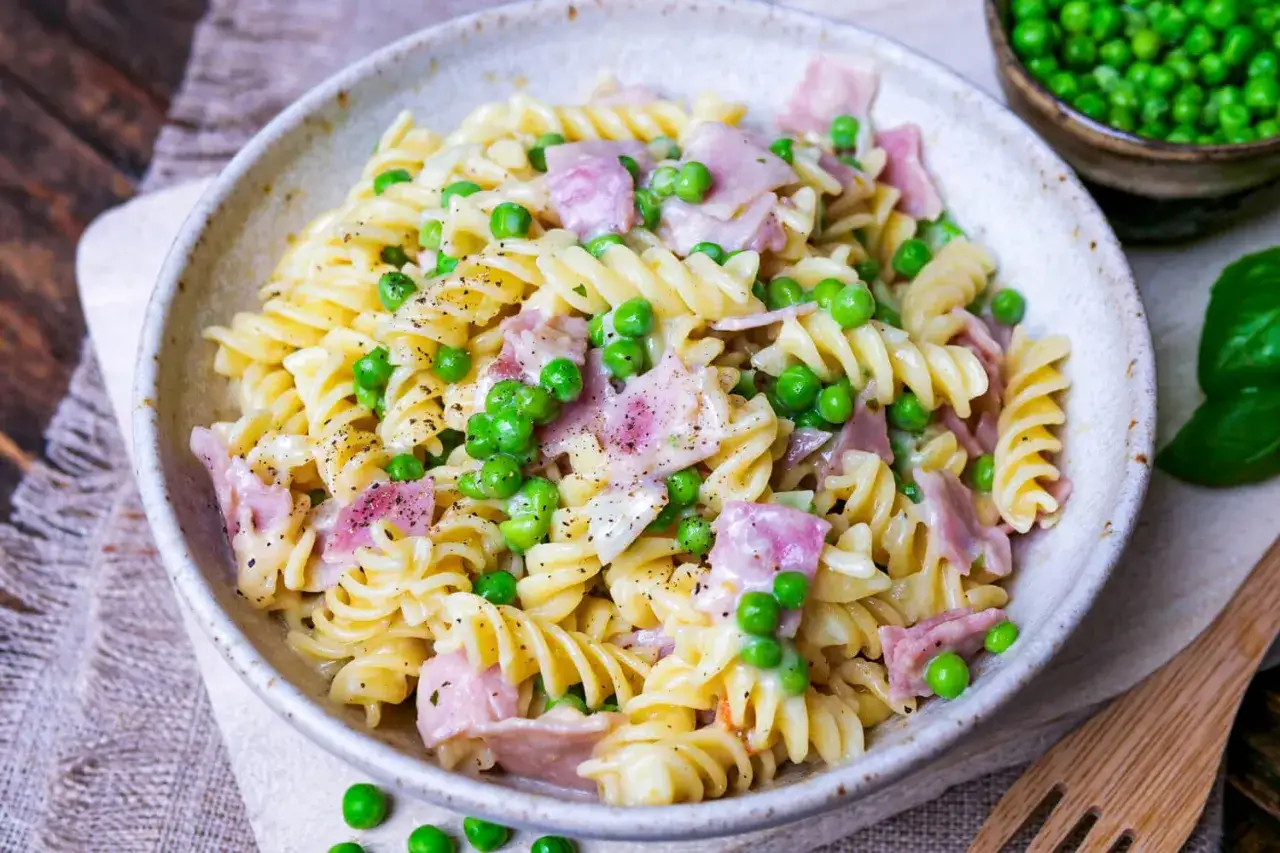 Fusilli-Nudeln mit Erbsen und Schinken in cremiger Schinken Sahne Sauce, bestreut mit schwarzem Pfeffer.