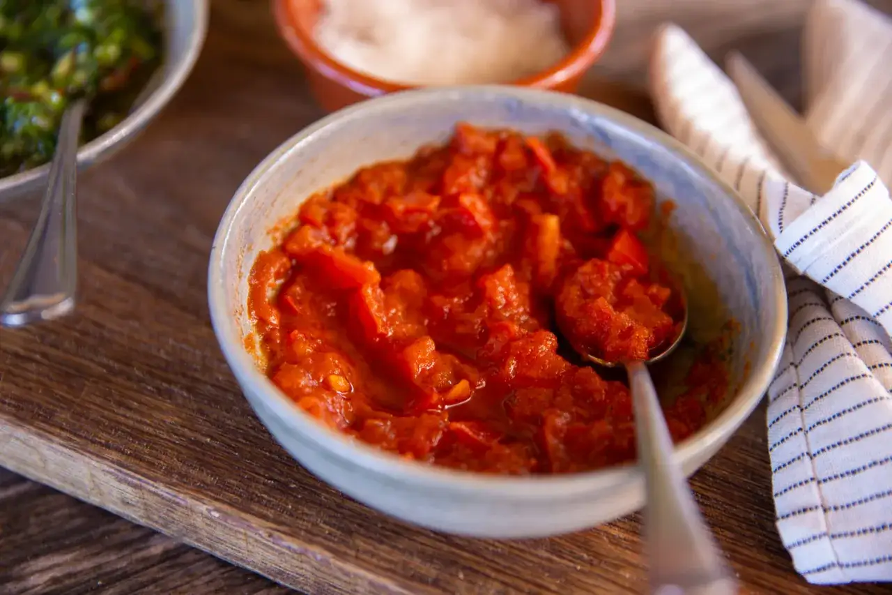 Schüssel mit selbstgemachtem Tomatenketchup, daneben eine Schüssel mit grüner Sauce und eine mit Salz.