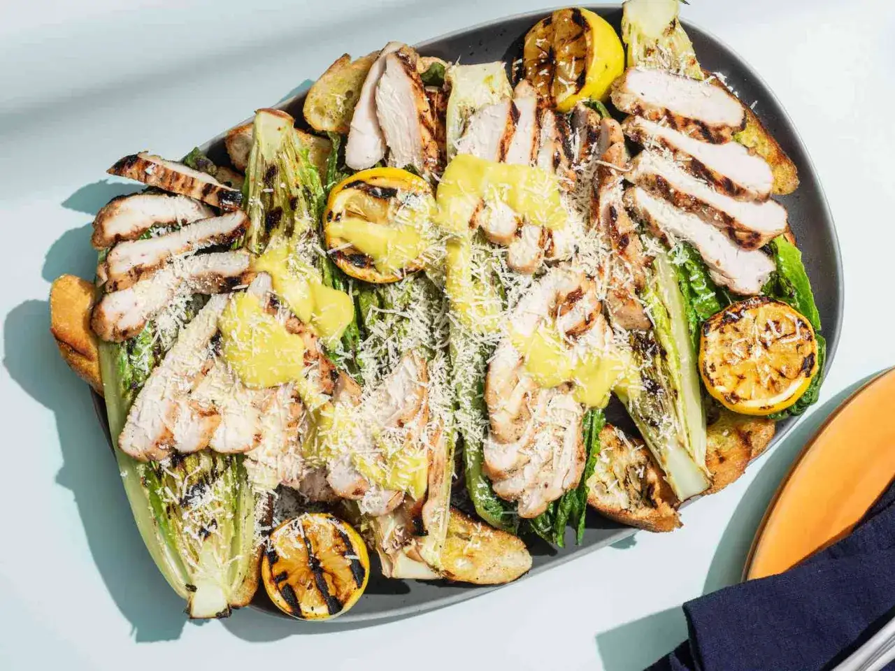 Gegrillter Romana-Salat mit Hähnchenbrust, Croutons und Zitronenspalten – perfekte Salate zum Grillen.