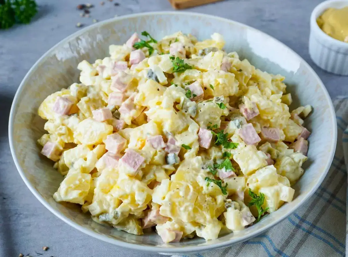 Sch&uuml;ssel mit Omas Kartoffelsalat mit Mayonnaise, garniert mit Petersilie. Ein Klassiker, der immer schmeckt!