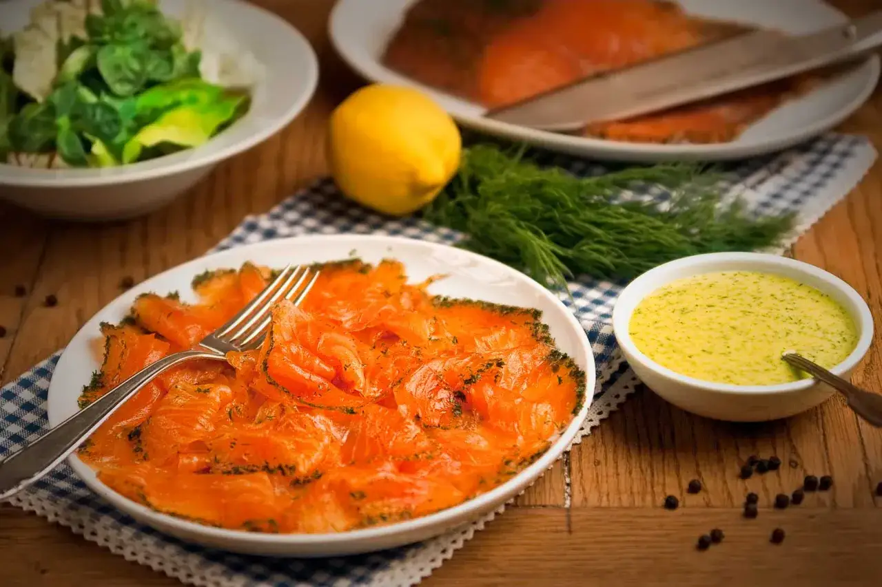 Eine k&ouml;stliche gebeizter Lachs Vorspeise, garniert mit Dill, serviert mit einer cremigen Sauce und Zitrone.