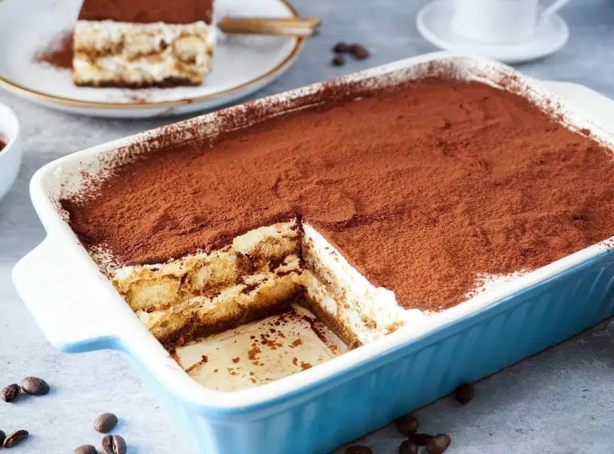 Ein köstliches Tiramisu mit Sahne und Mascarpone, bestäubt mit Kakao. Ein Stück wurde bereits entnommen.